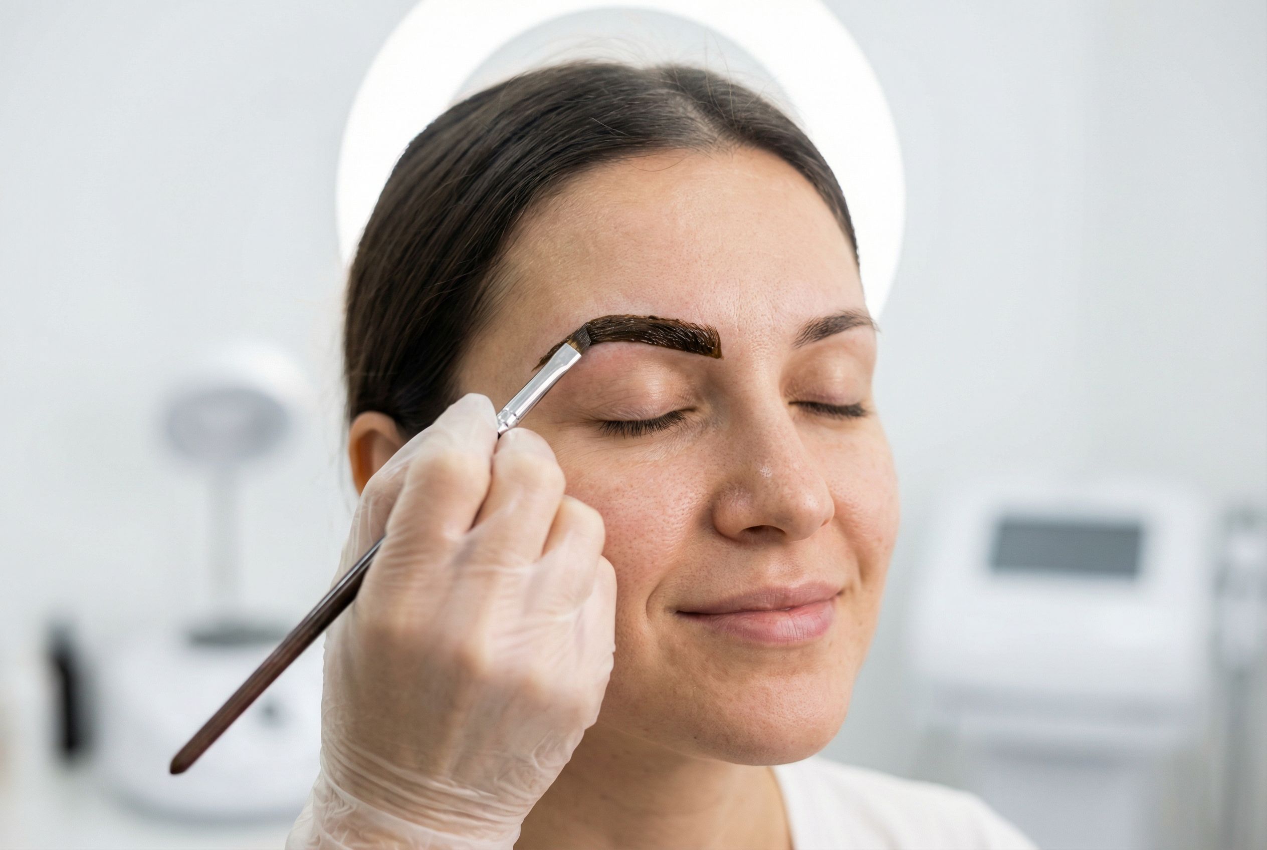 Henna brow treatment being applied with a fine brush in a modern salon